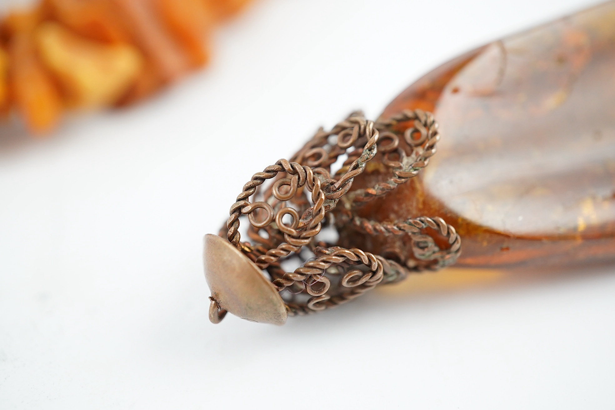 A long single strand unpolished amber necklace, 162cm and a gilt metal mounted amber pendant, gross weight 205 grams. Condition - fair